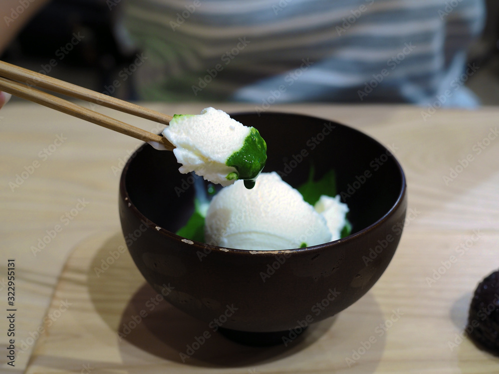 A bowl of fresh milk ice cream flavored over green tea or Japanese matcha on wooden tray. A bowl of fresh milk ice cream flavored over green tea or Japanese matcha on wooden tray.