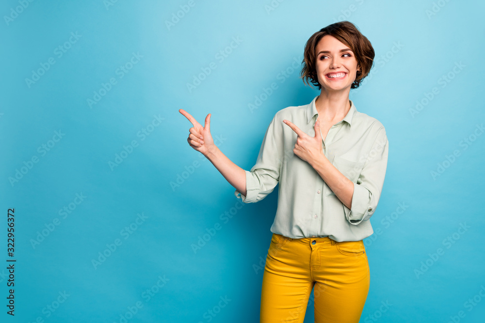 Photo of attractive pretty lady indicating fingers look empty space advising cool low prices shopping wear casual green shirt yellow trousers isolated blue color background