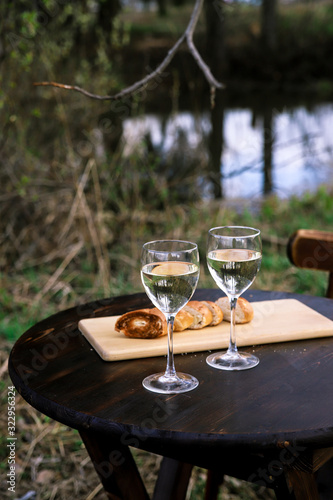 Spring picnic on nature     white wine in glasses and grill bread on wooden round table