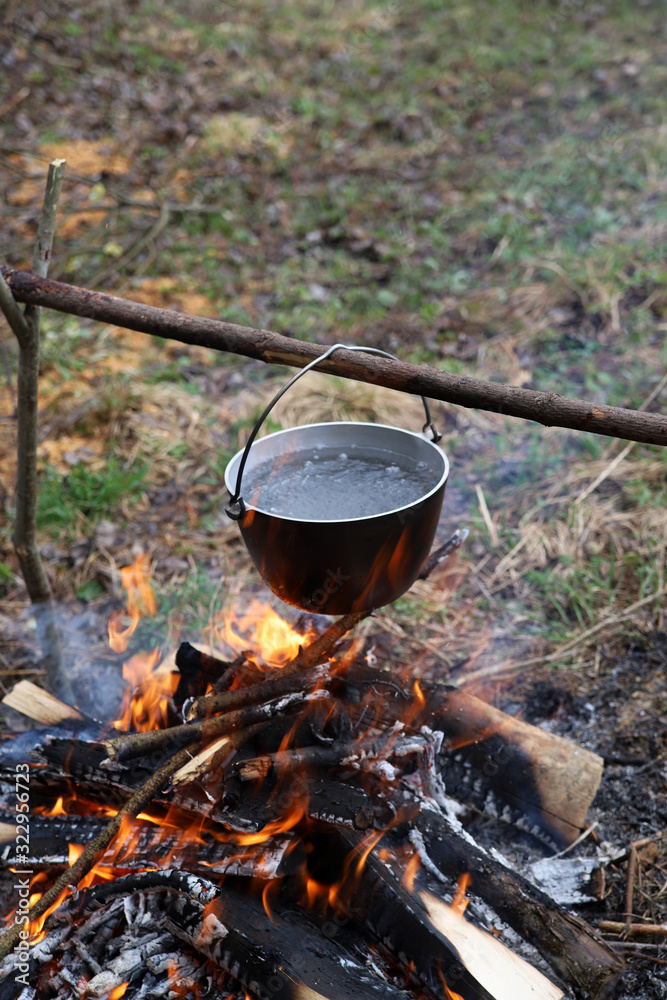 Cauldron on fire in a hiking trip. Water is boiling in metal pot on campfire. Cooking tea or food in the camp in nature Cauldron on fire in a hiking trip. Water is boiling in metal pot on campfire. Cooking tea or food in the camp in nature
