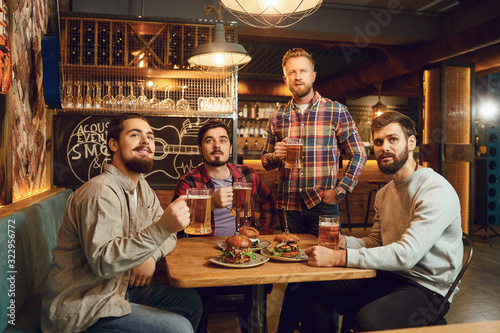 A group of guys watching sports on tv in a pub bar.