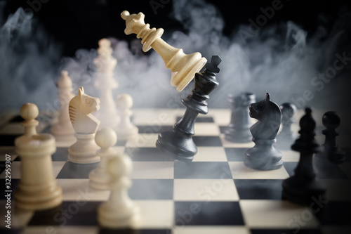 фотографія chess queen beats king between other pieces on the chessboard, much smoke over t