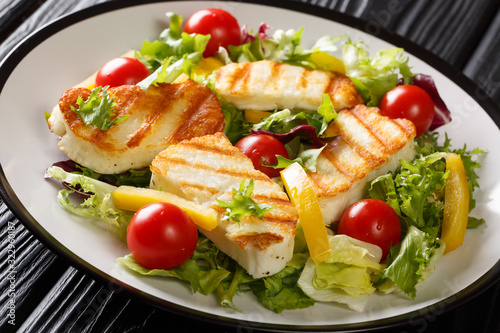 Cheese salad with grilled halloumi with fresh vegetables close-up on the plate. horizontal