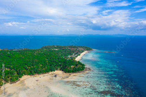 Flying above busy tropical island port filled with boats and ferries. Countless ships sail to and from bustling harbor on exotic beach. Picturesque shot of fleet of anchored longtail boats.