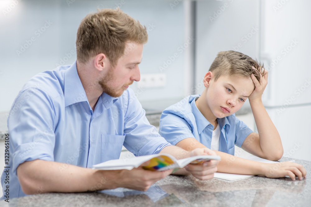 Father and his son doing homework together at home Father and his son doing homework together at home