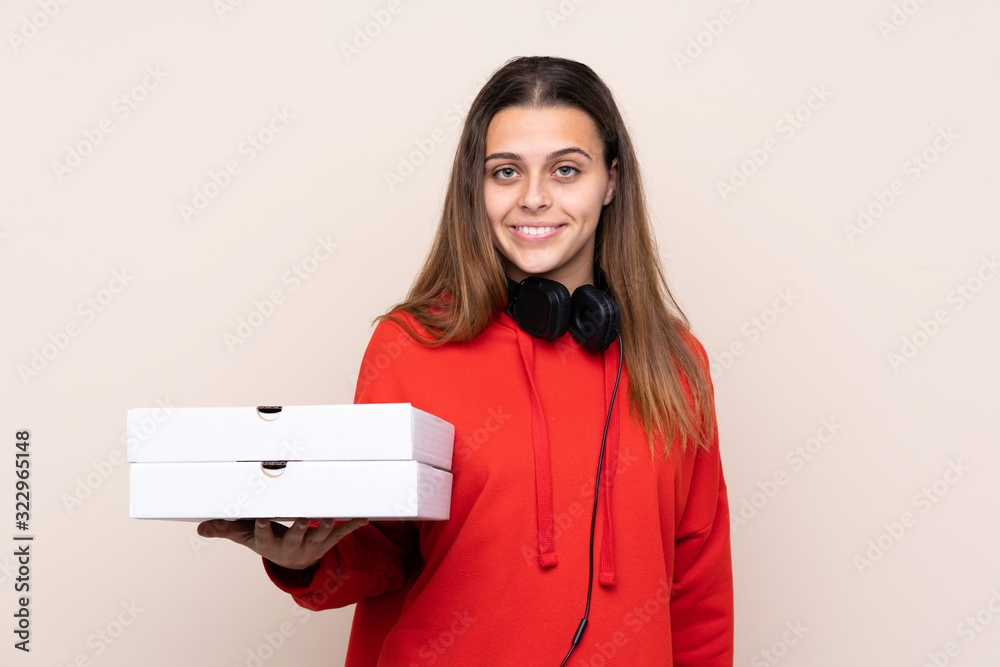 Pizza delivery girl holding a pizza over isolated wall smiling a lot Pizza delivery girl holding a pizza over isolated wall smiling a lot