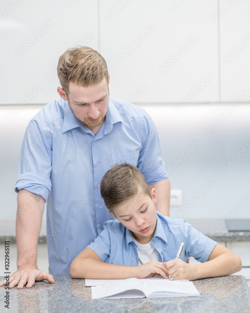 Fototapeta premium Father helps his son doing homework at home