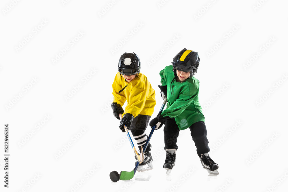 Little hockey players with the sticks on ice court and white studio background. Sportsboys wearing equipment and helmet practicing. Concept of sport, healthy lifestyle, motion, movement, action. Little hockey players with the sticks on ice court and white studio background. Sportsboys wearing equipment and helmet practicing. Concept of sport, healthy lifestyle, motion, movement, action.