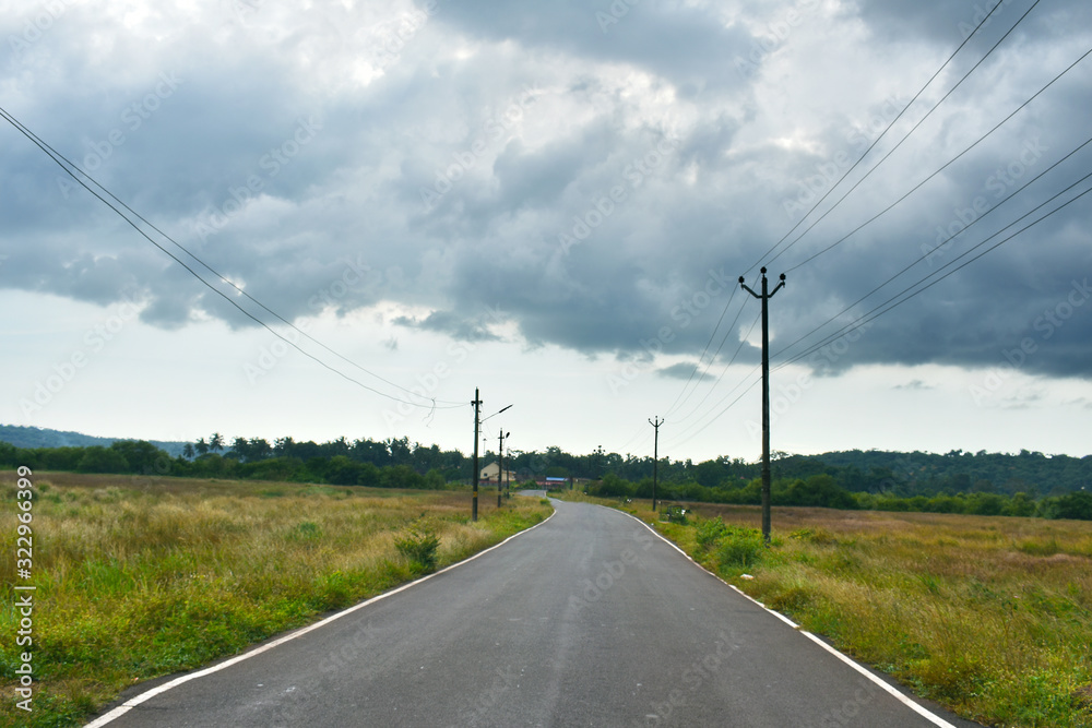 Beautiful Empty road in Autumn season with green fields and cloudy sky in Goa Beautiful Empty road in Autumn season with green fields and cloudy sky in Goa