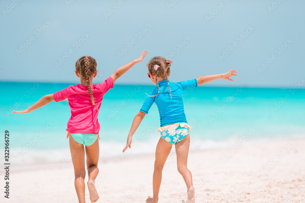 Little girls having fun at tropical beach playing together at shallow water Little girls having fun at tropical beach playing together at shallow water