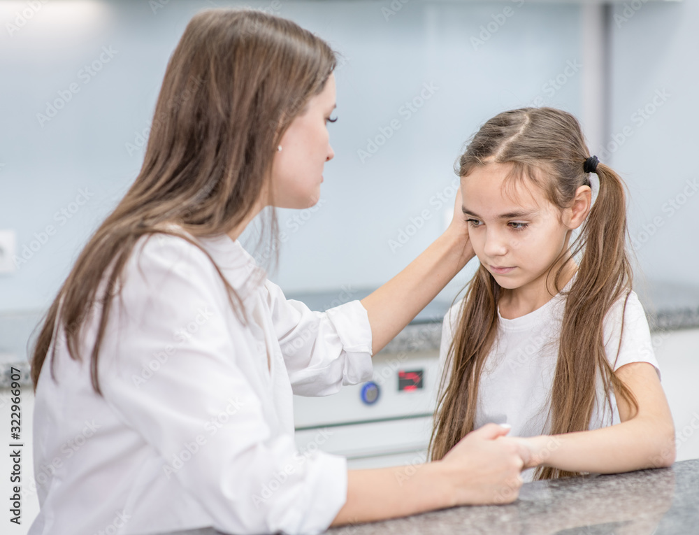 Fototapeta premium Mother calms her upset daughter while talking with her at home