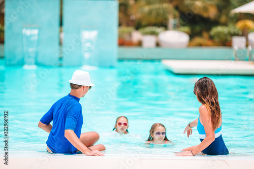 Young family with two kids enjoy summer vacation in outdoor pool