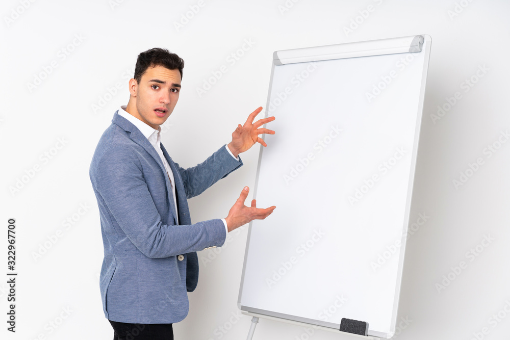 Young caucasian handsome man isolated on purple background giving a presentation on white board Young caucasian handsome man isolated on purple background giving a presentation on white board