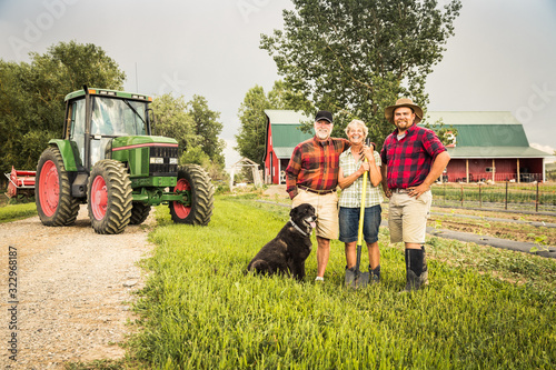 Portrait of farming family laughing after long day of work with dag, tractor and barn. Laurel, Montana, USA photo