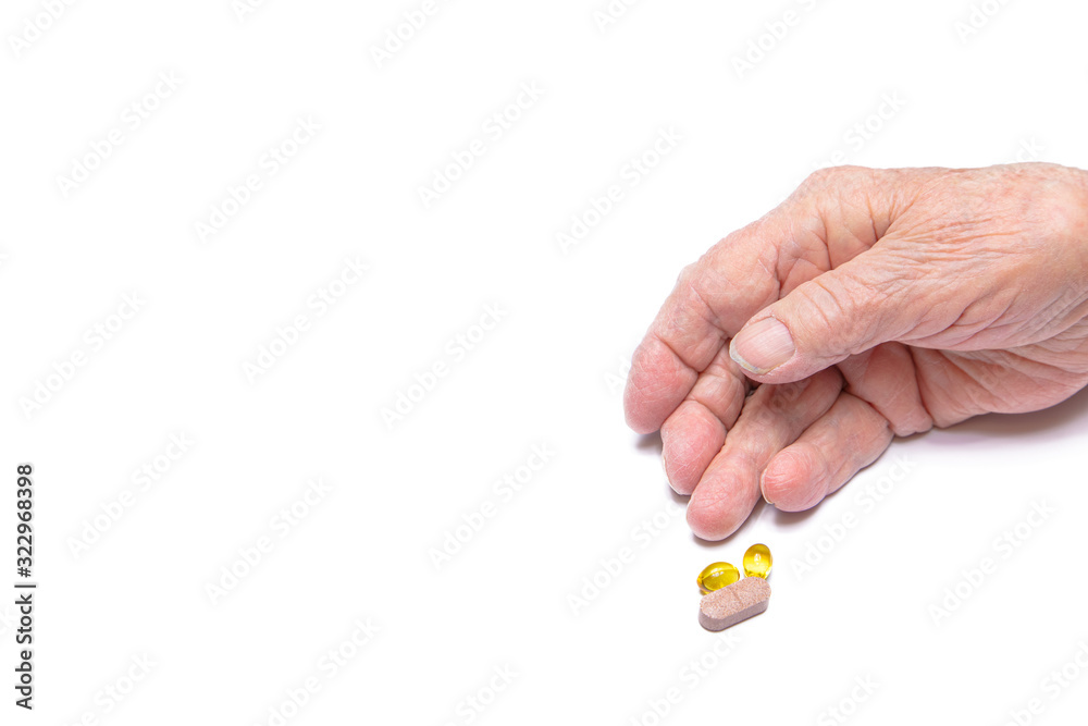 Close-up of an old woman's hand holding pills. White background.Concept of illness, flu, old age, Coronavirus Close-up of an old woman's hand holding pills. White background.Concept of illness, flu, old age, Coronavirus