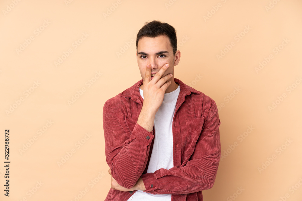 Young caucasian handsome man isolated on beige background surprised and shocked while looking right