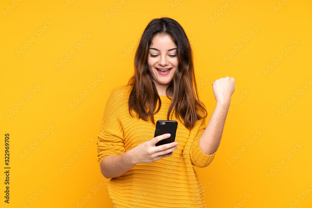 Young caucasian woman isolated on yellow background with phone in victory position Young caucasian woman isolated on yellow background with phone in victory position