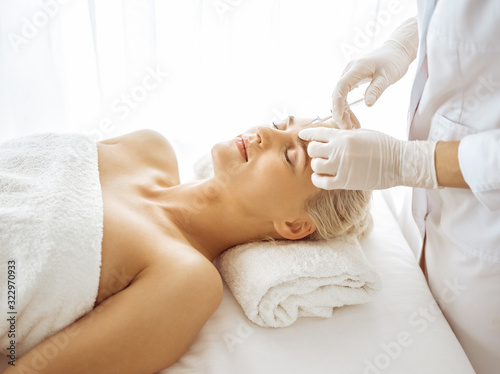 Beautician doctor hands doing beauty procedure to female face with syringe. Cosmetic medicine and surgery, beauty injections concept