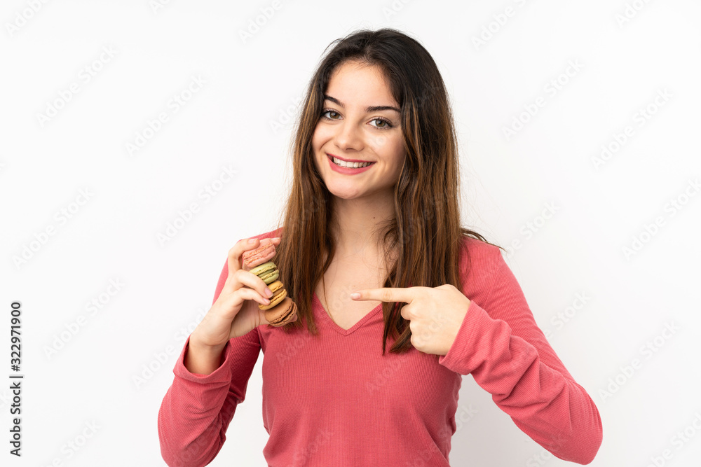 Young caucasian woman isolated on pink background holding colorful French macarons and pointing it Young caucasian woman isolated on pink background holding colorful French macarons and pointing it