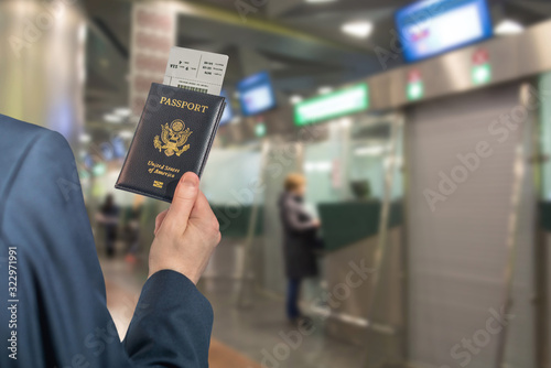 Man (businessman)  in a blue suit holding american passport with boarding pass in the airport opposite Immigration and passport control. concept. America. USA