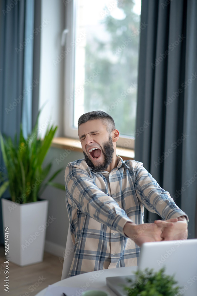 Young man sitting yawning with his eyes closed. Young man sitting yawning with his eyes closed.