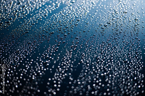 close up of raindrops on blue car bonnet