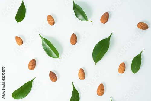 almonds and green leaves isolated on a white background. spring composition, top view. nutritious nut, healthy nutrition. flat lay