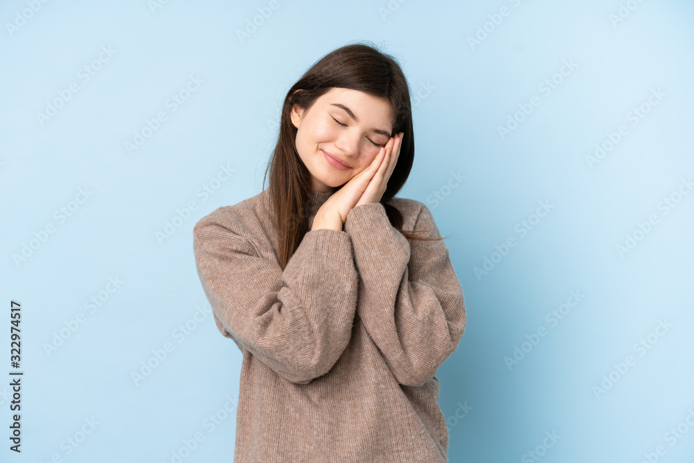 Young Ukrainian teenager girl wearing a sweater over isolated blue background making sleep gesture in dorable expression Young Ukrainian teenager girl wearing a sweater over isolated blue background making sleep gesture in dorable expression