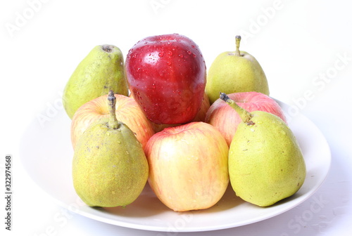 Apples and pears with water drops on white plate