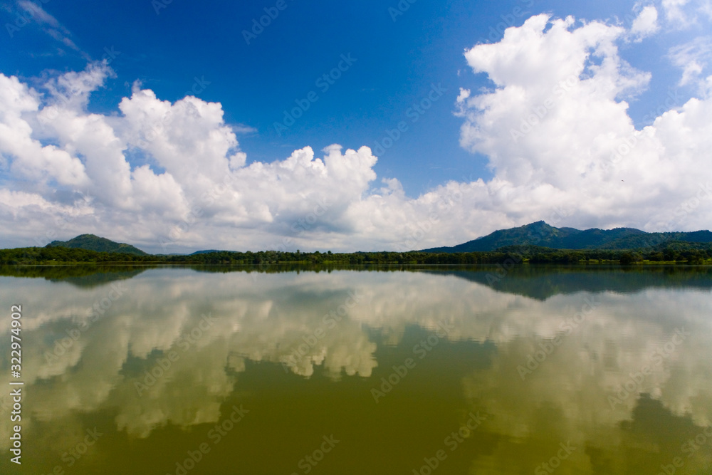 Mountains and a cloud in the sky are reflected in the lake.
