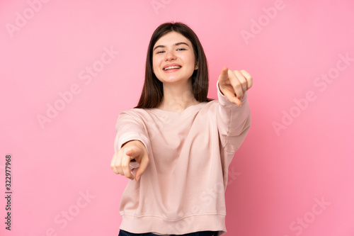 Young Ukrainian teenager girl over isolated pink background points finger at you while smiling © luismolinero