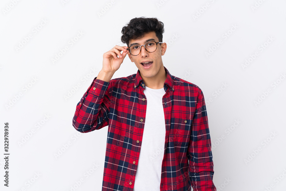 Young Argentinian man over isolated white background with glasses and surprised Young Argentinian man over isolated white background with glasses and surprised