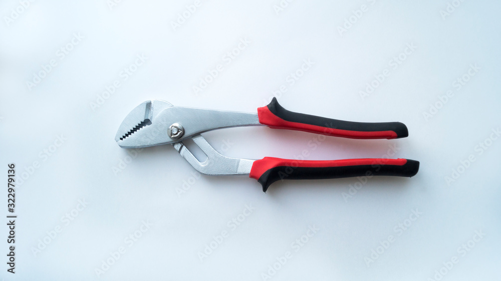Obraz premium A removable steel key with a red-black handle lies in the closed state on a white background. Repair tool.