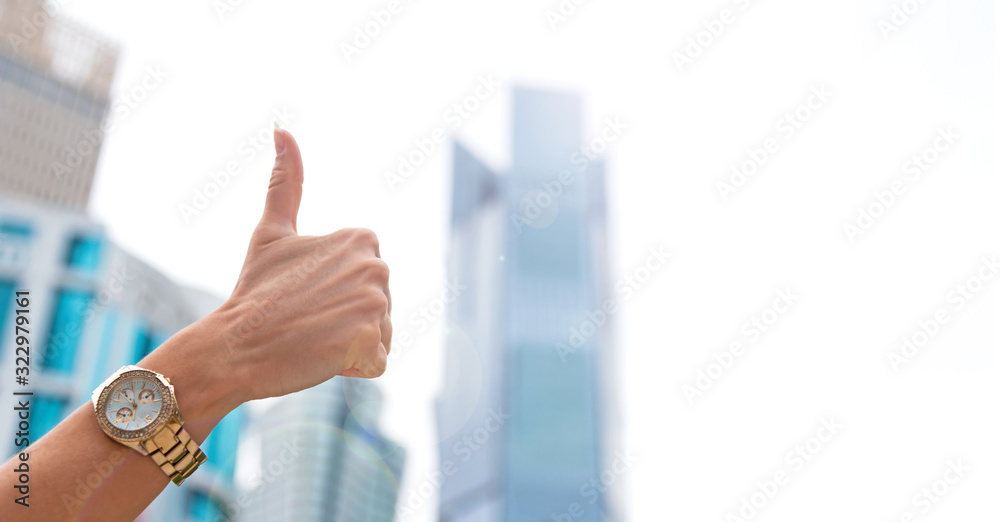 Hand with thumbs up gesture against skyscrapers of modern cityscape. Hand with thumbs up gesture against skyscrapers of modern cityscape.