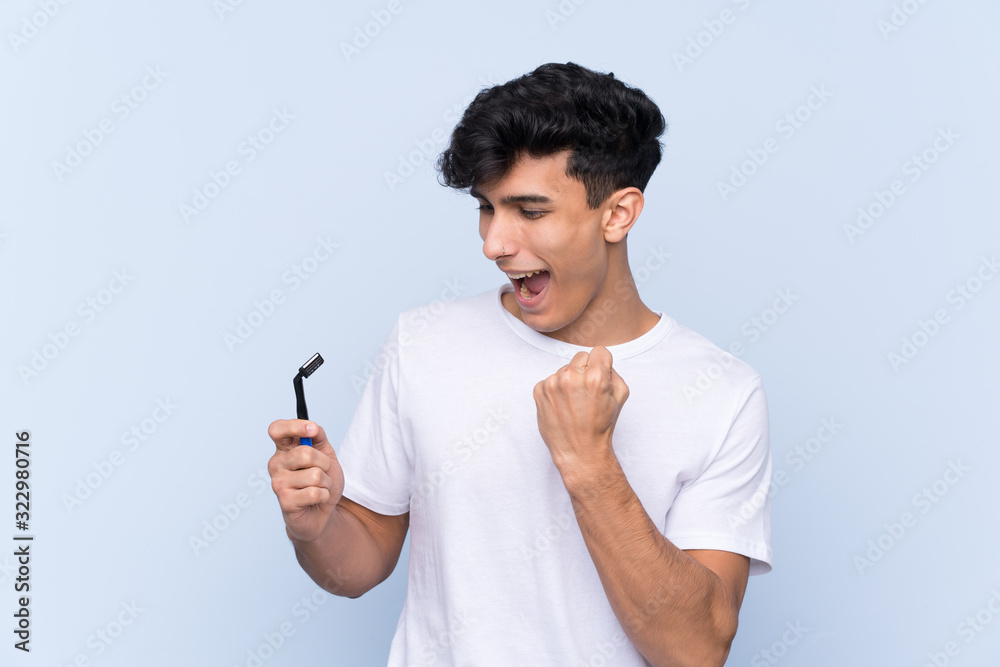 Man shaving his beard over isolated white background celebrating a victory Man shaving his beard over isolated white background celebrating a victory