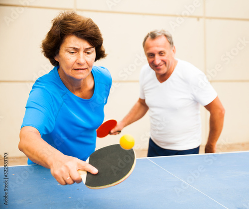 Happy mature man and woman playing table tennis