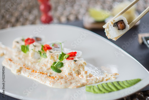 Traditional rolls with fish and rice on a white plate with sauce and wasabi. Japanese food.