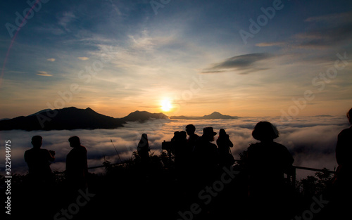 Silhouette of tourists looking at mist and mountain with blue sky in nature landscape