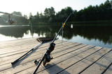 Carp fishing on beautiful blue lake with carp rods and rod pods in the summer morning. Fishing from the wooden platform.