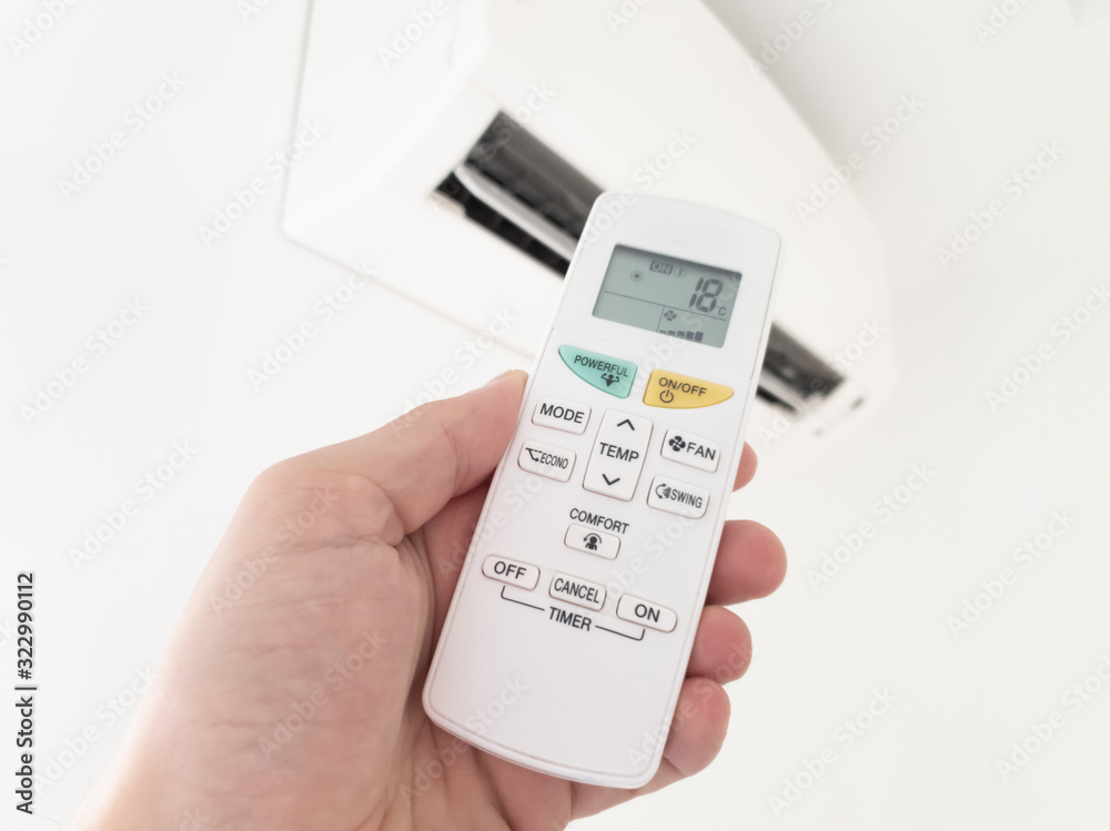 Modern airconditioner unit with a hand holding a remote. Modern airconditioner unit with a hand holding a remote.
