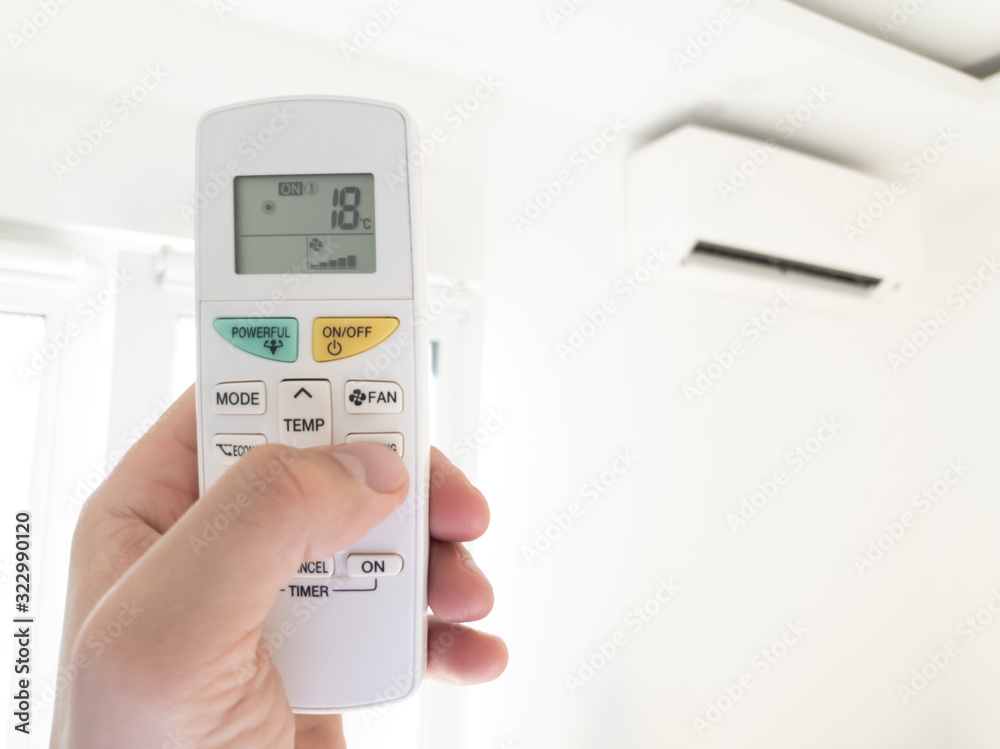 Modern airconditioner unit with a hand holding a remote. Modern airconditioner unit with a hand holding a remote.