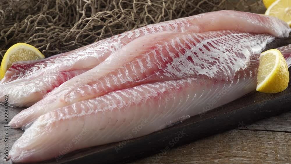 Fresh haddock fillets on a cutting board with lemon wedges. Fresh haddock fillets on a cutting board with lemon wedges.