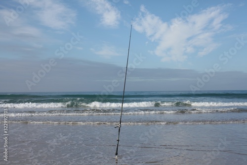 Fishing rod on the beach by waves