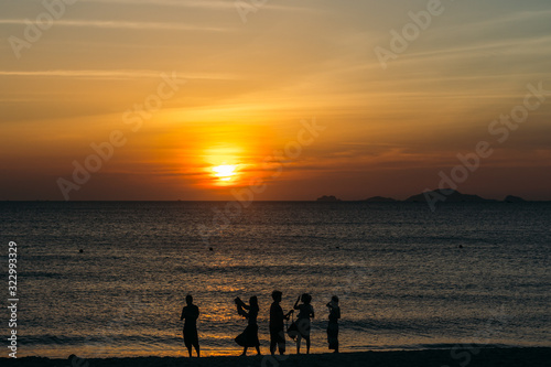 Colorful dawn, sunset on a calm sea, sunrise. Beautiful sea background. A charming start to the day. Silhouette of a group of people on a background of the sea