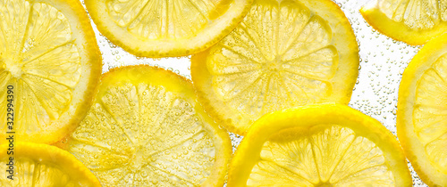 Slices of lemon in water with air bubbles on white background. Close up.