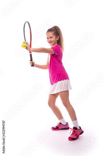 A young  girl with a tennis racket and a ball   stands in a pose ready to throw © rozaivn58
