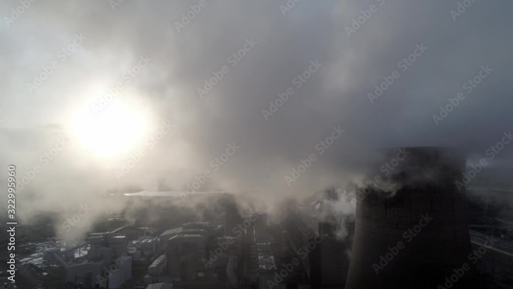 Aerial pull back reveal of UK power station cooling towers through atmospheric steam emissions at sunrise. Aerial pull back reveal of UK power station cooling towers through atmospheric steam emissions at sunrise.