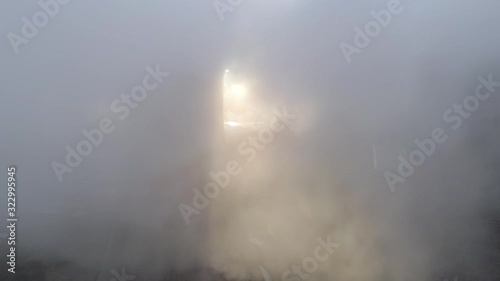 Aerial shot of UK power station cooling towers through smoke steam emissions at sunrise.