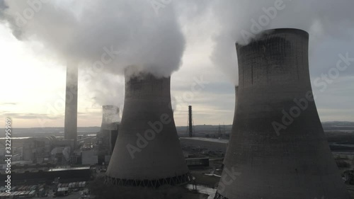 Aerial view rising to UK power station cooling towers atmospheric smoke steam emissions at sunrise.