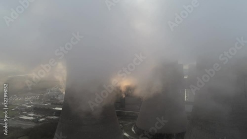 Aerial view of UK power station cooling towers smoke steam emissions cloudscape atmosphere at sunrise.